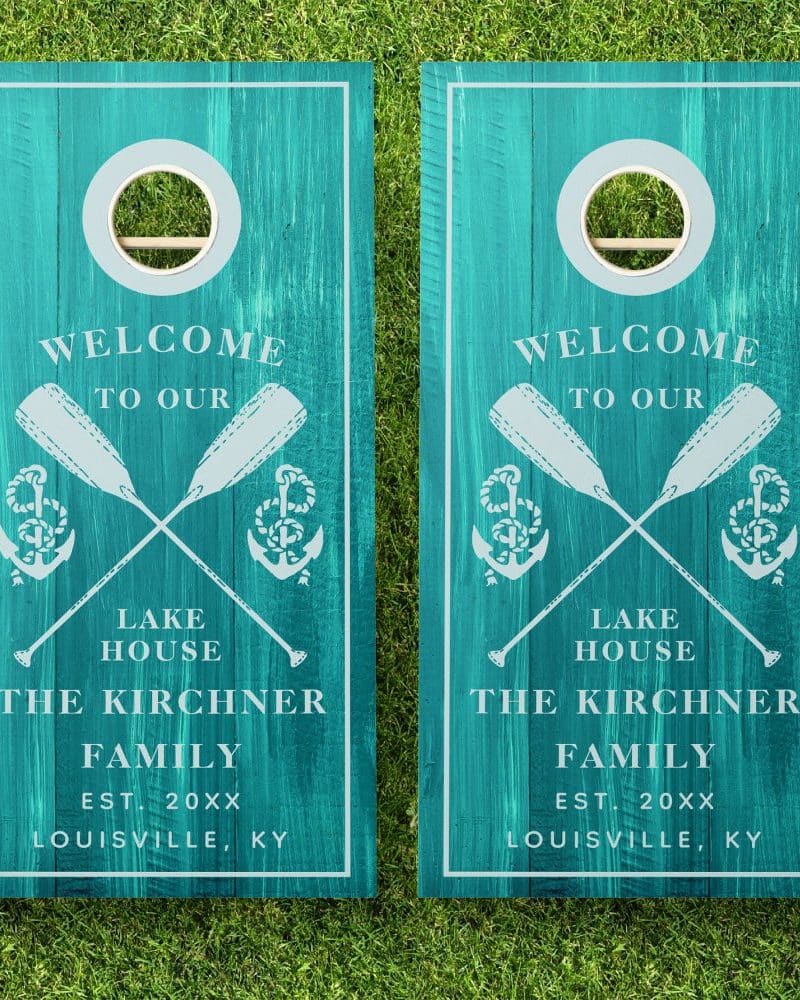 Pair of teal blue cornhole boards with a welcome message, crossed oars, anchors, and the Kirchner family name.