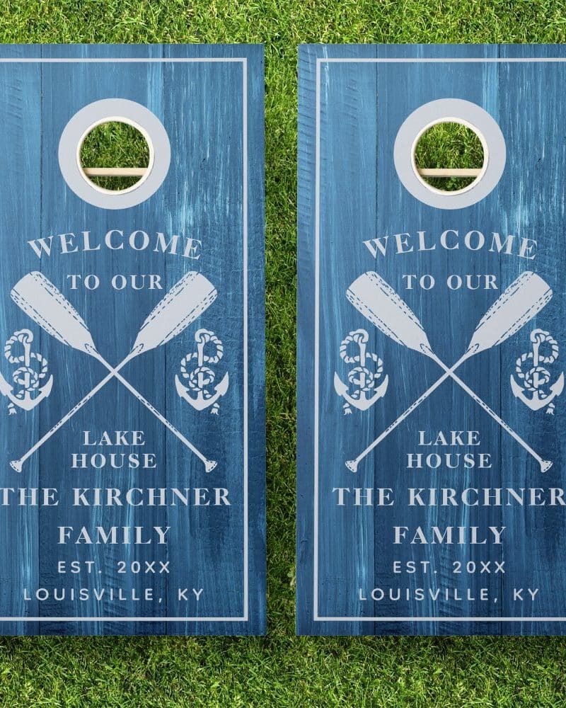 Two blue wooden cornhole boards with a nautical theme. Each board displays a welcome message, crossed oars, anchors, and the Kirchner family name and location.