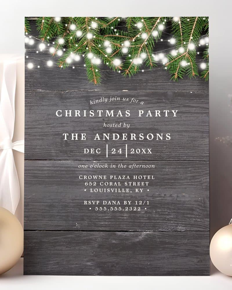 Christmas party invitation with wood background, evergreen boughs, and string lights.