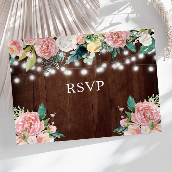 Rsvp Card With Pink And Peach Floral Watercolor Design And String Lights On A Dark Wood Background.