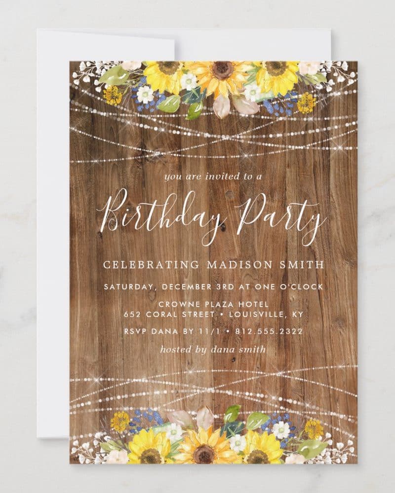 Birthday party invitation with sunflowers and string lights on a wood background.