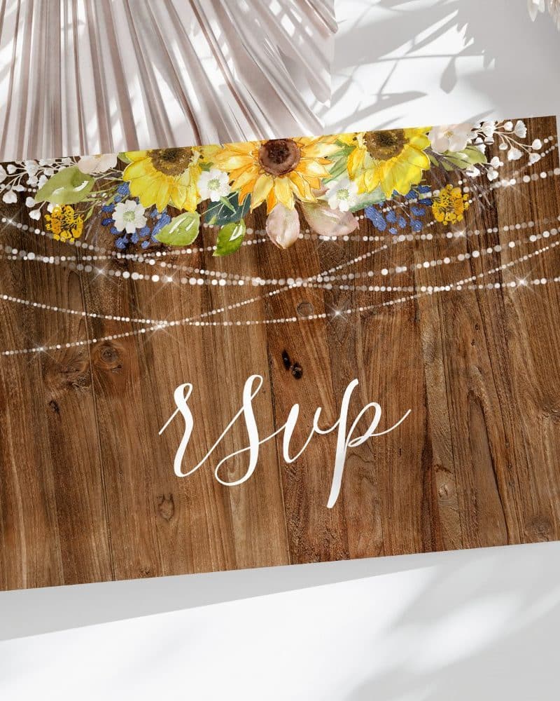 RSVP card with sunflowers and string lights on a wood background.