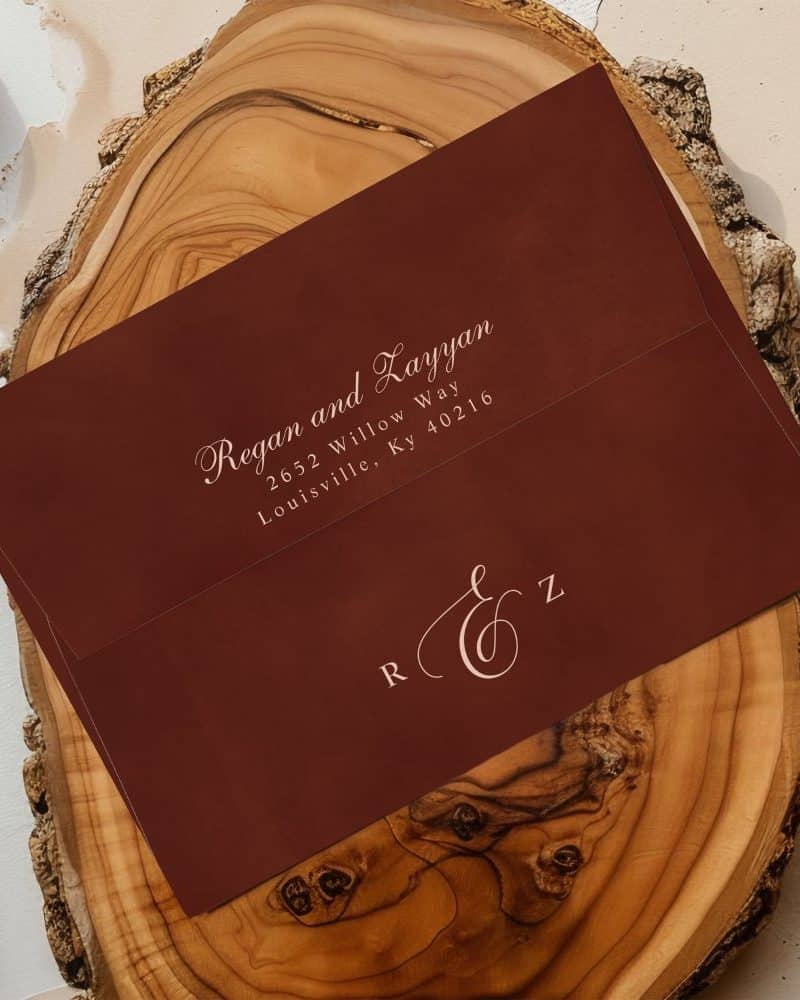 Dark red envelope with light pink lettering showing a couple's name and address, and their monogram.