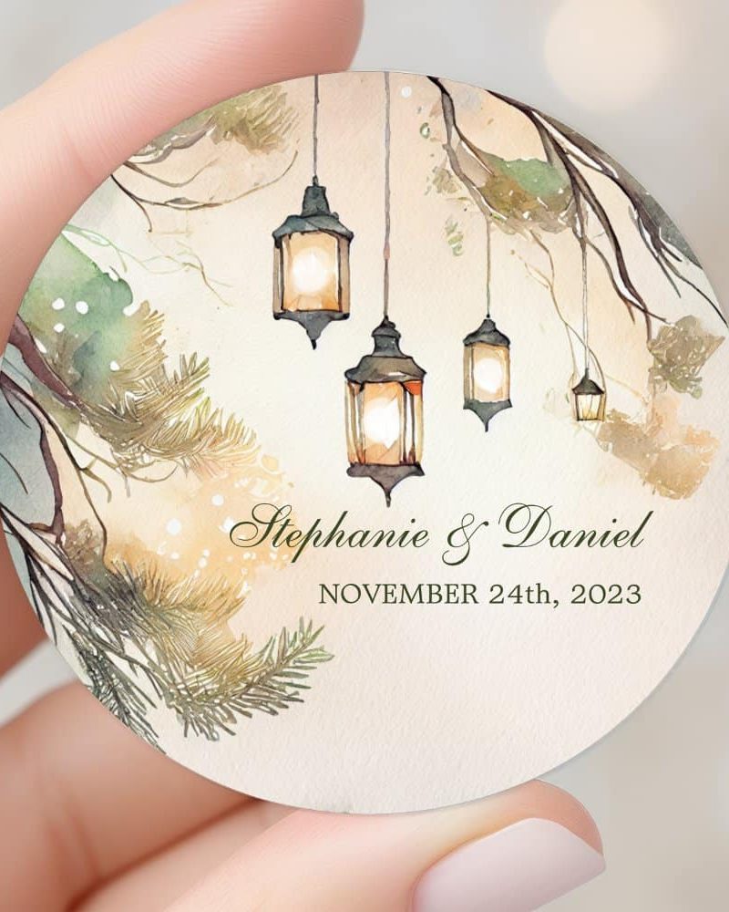 Round wedding invitation featuring watercolor lanterns hanging from tree branches, with Stephanie & Daniel's names and wedding date, November 24th, 2023.