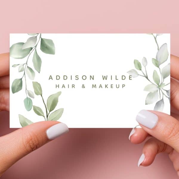 Two Hands Hold A Business Card Featuring A Watercolor Design Of Green Leaves And The Text Addison Wilde Hair &Amp; Makeup.