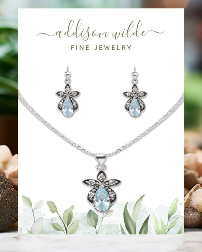 Silver necklace and earrings set with light blue teardrop gemstones and smaller, clear stones.