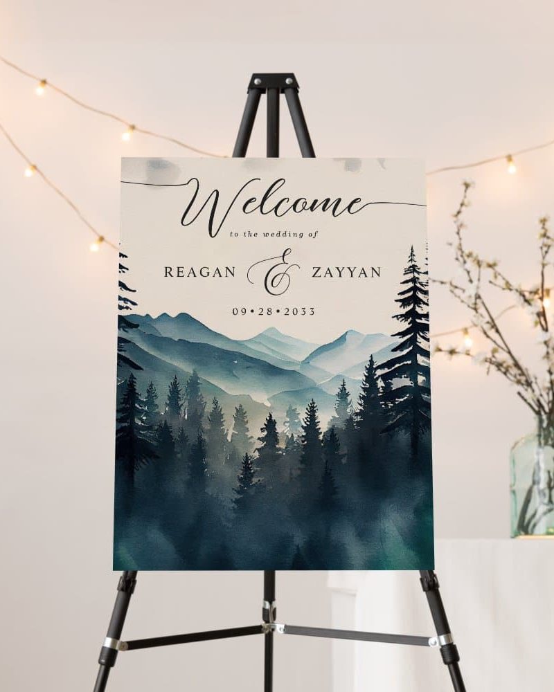 Wedding welcome sign with watercolor mountains and forest, announcing Reagan and Zayyan's wedding on September 28, 2033.
