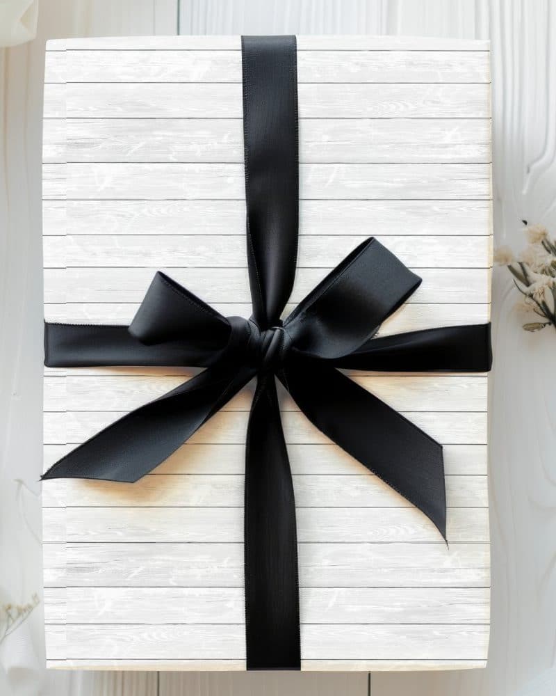 White gift box with a large black ribbon bow.