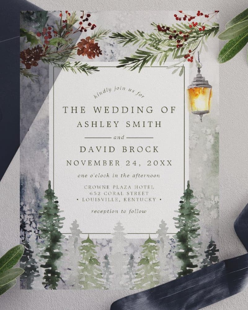 Winter wedding invitation featuring a watercolor painting of pine trees and a lit lantern.