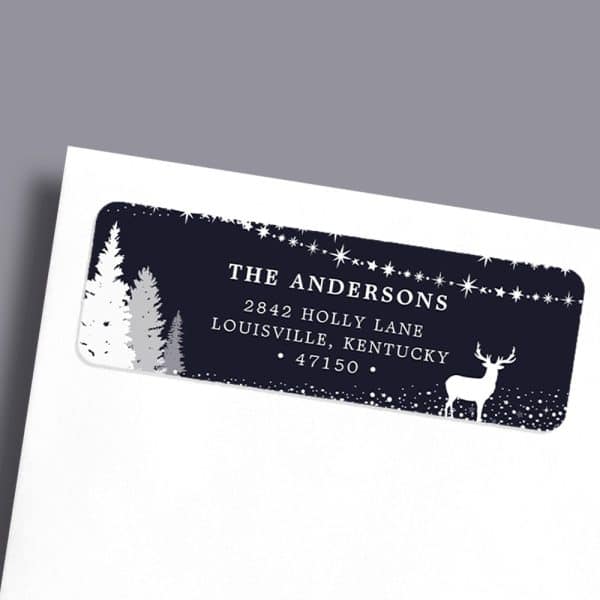 A Dark Blue Holiday Return Address Label With White Silhouettes Of Pine Trees, A Deer, And Stars. The Andersons' Address Is Printed In White.