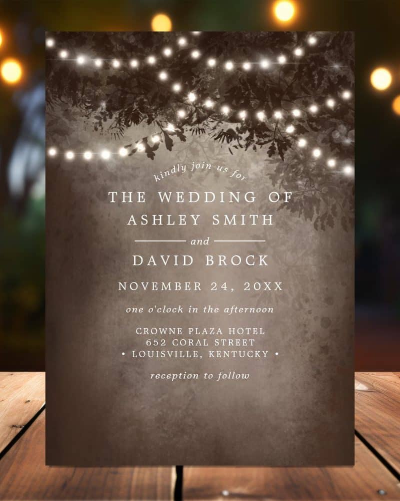 Wedding invitation for Ashley Smith and David Brock, November 24, at the Crowne Plaza Hotel in Louisville, Kentucky. String lights and trees are depicted in the background.
