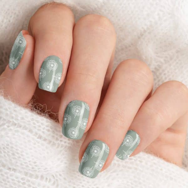 Close-Up Of A Hand With Pale Green Nails Decorated With A White Dandelion Pattern.