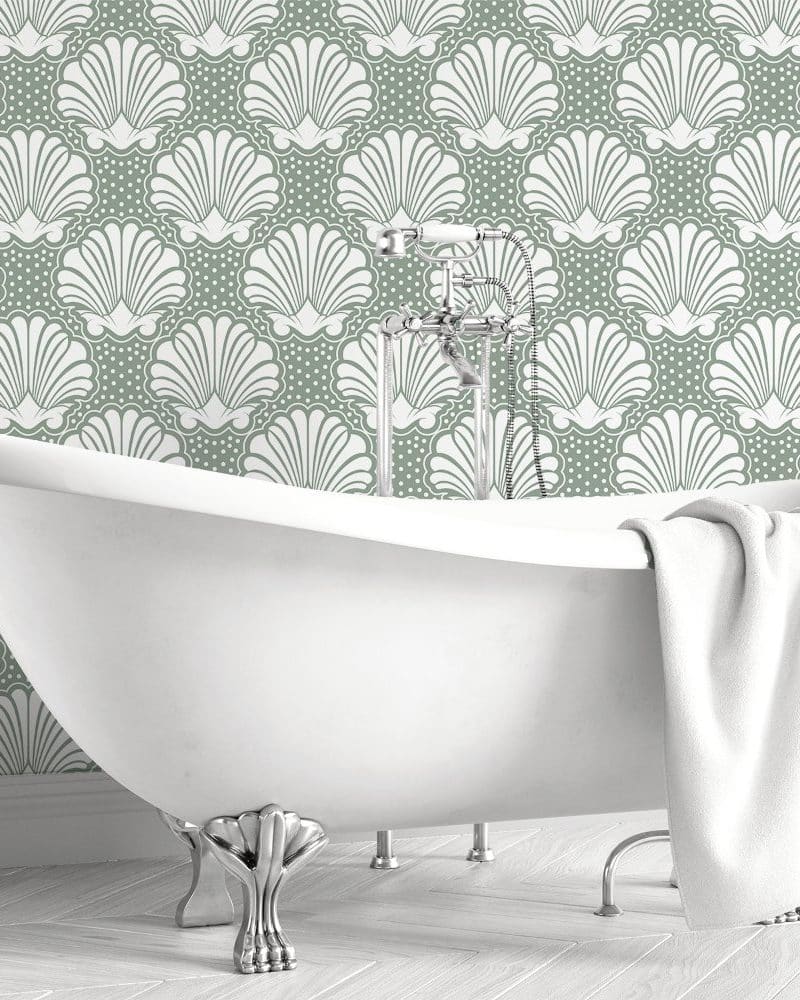 White clawfoot bathtub in front of sage green shell patterned wallpaper.