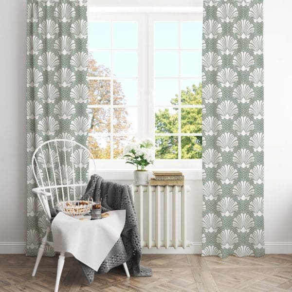 Sage Green Curtains With A White Seashell Pattern Hang In A Window, Partially Obscuring A View Of A White Chair And Small Table.