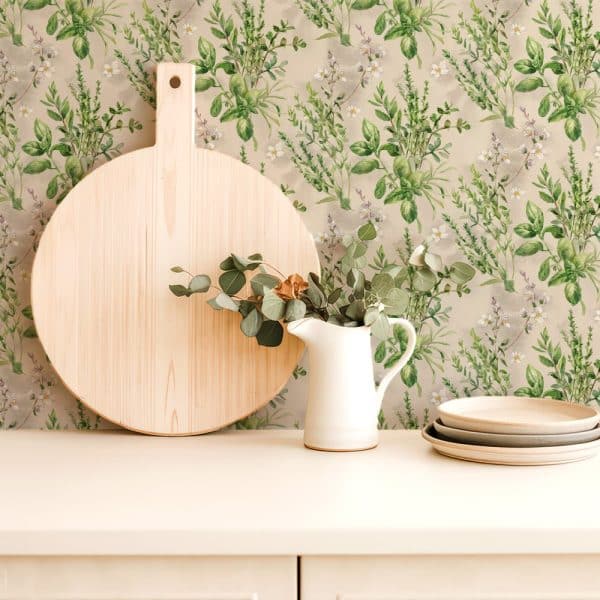 Large Wooden Cutting Board, White Pitcher With Eucalyptus Sprigs, And Stacked Plates Against A Backdrop Of Herb-Patterned Wallpaper.
