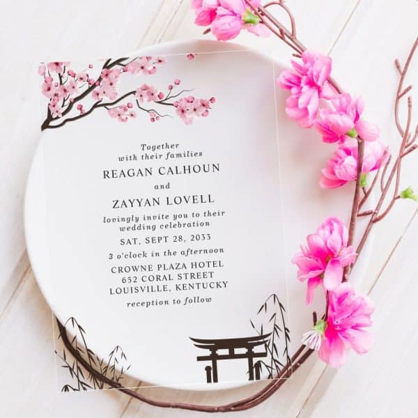 Clear Wedding Invitation With Pink Cherry Blossoms And A Torii Gate, Announcing The Wedding Of Reagan Calhoun And Zayyan Lovell.