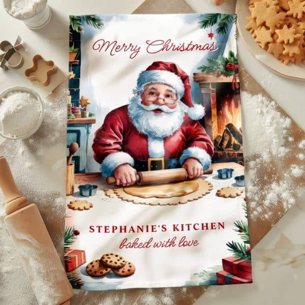 Christmas Tea Towel Featuring Santa Claus Baking Cookies In A Kitchen Scene. The Text &Quot;Stephanie'S Kitchen Baked With Love&Quot; Is Also Visible.