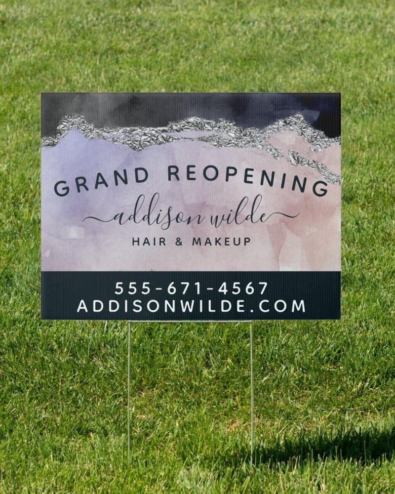 A grand reopening announcement for Addison Wilde Hair & Makeup, displayed on a yard sign with a watercolor design and silver accents.