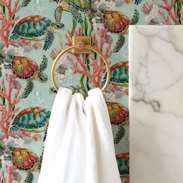 White Towel Hanging On A Gold Ring Against A Teal Wallpaper Featuring Colorful Sea Turtles And Coral.