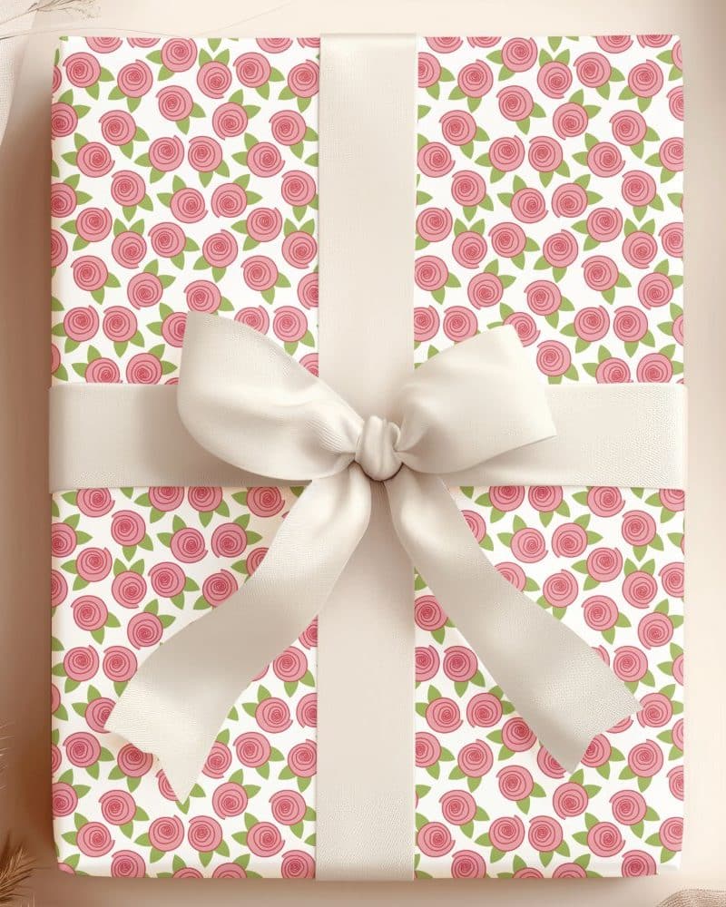 A gift wrapped in pink rose patterned paper with a cream-colored ribbon.