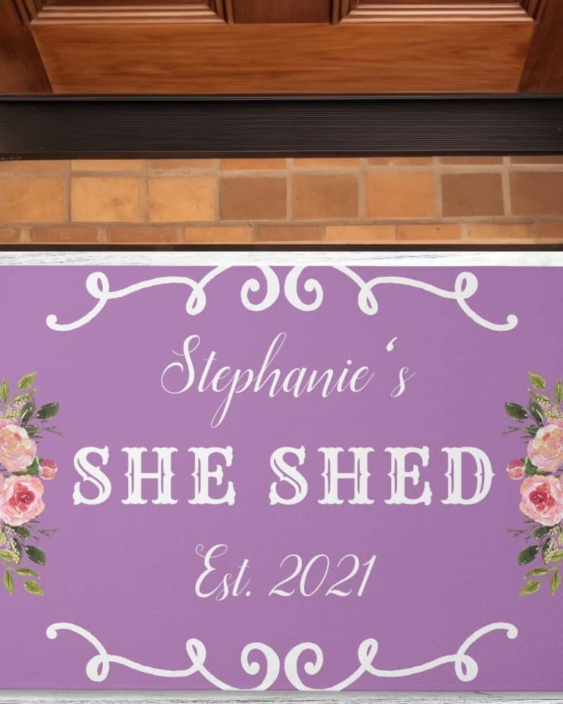 Purple doormat with Stephanie's She Shed Est. 2021 in white lettering and floral designs.