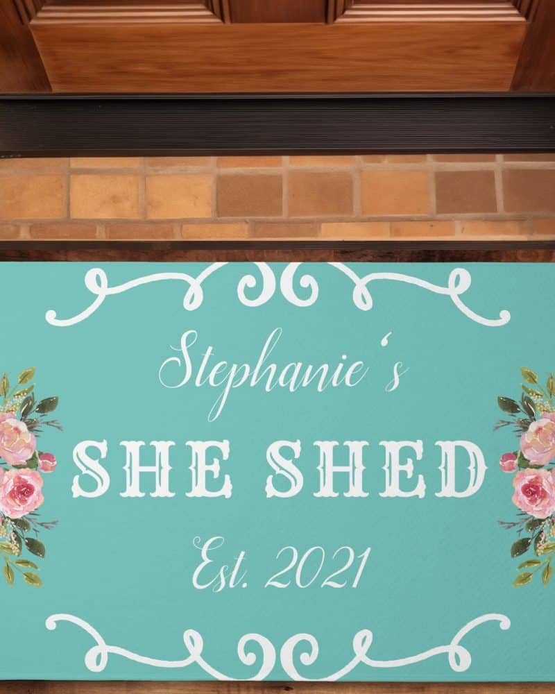 Teal doormat with Stephane's She Shed Est. 2021 and floral accents.