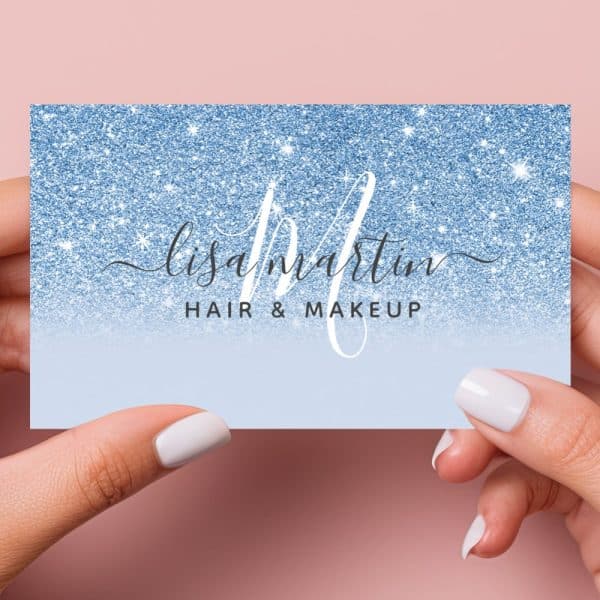 Two Hands Hold A Blue Glitter Business Card For Lisa Martin Hair &Amp; Makeup.