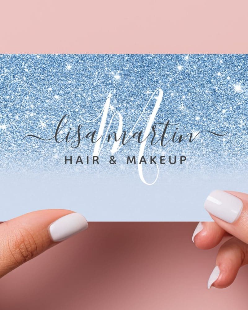 Two hands hold a blue glitter business card for Lisa Martin Hair & Makeup.