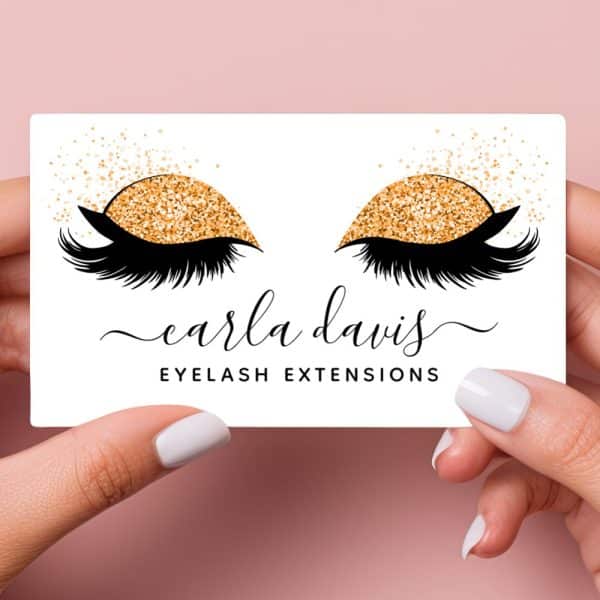 Business Card Featuring A Pair Of Eyes With Long Lashes And Gold Glitter Eyeshadow. The Text Carla Davis Eyelash Extensions Is Below.