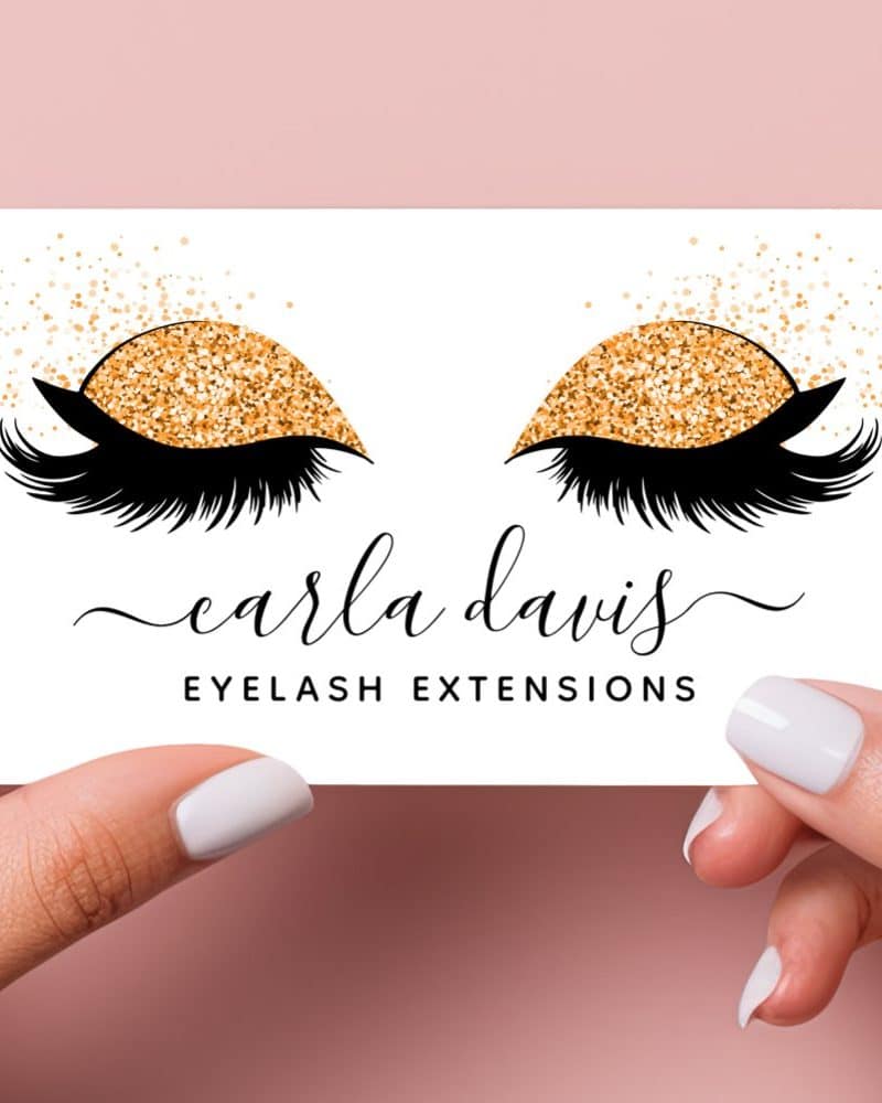 Business card featuring a pair of eyes with long lashes and gold glitter eyeshadow. The text Carla Davis Eyelash Extensions is below.