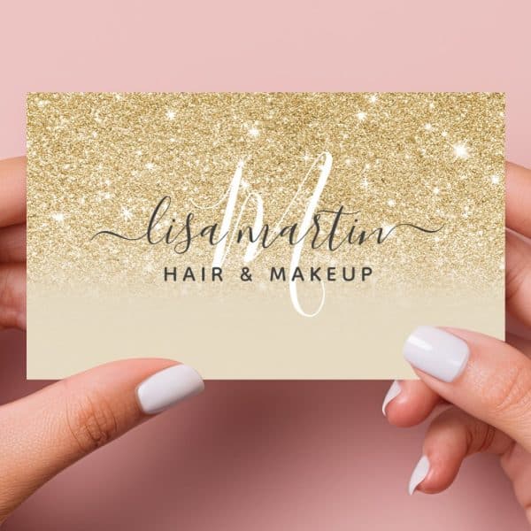 Two Hands Hold Up A Gold Glitter Business Card That Says Lisa Martin Hair &Amp; Makeup.