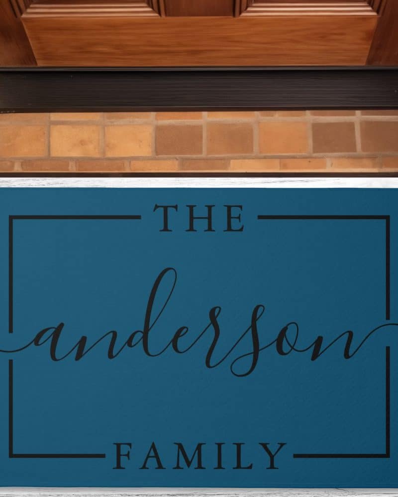 Teal doormat with the words The Anderson Family in a black sans-serif font.