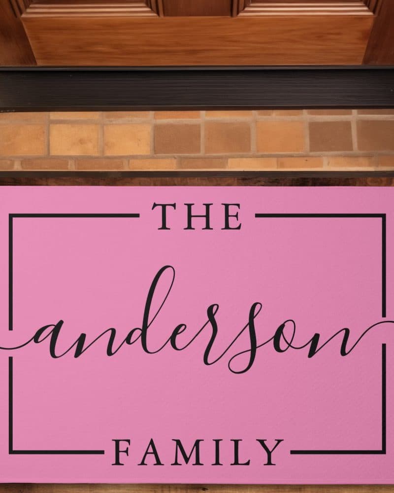 Pink doormat with the text The Anderson Family in a black sans-serif font.