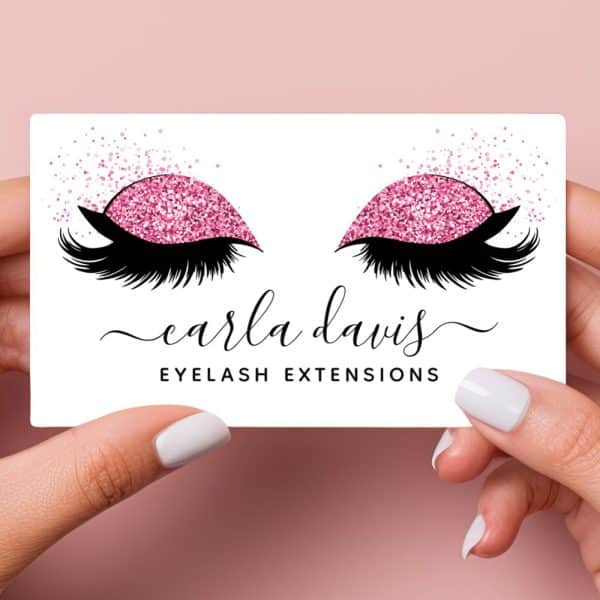A Business Card For Carla Davis Eyelash Extensions. The Card Features A Pair Of Eyes With Long Lashes And Pink Glitter Eyeshadow.