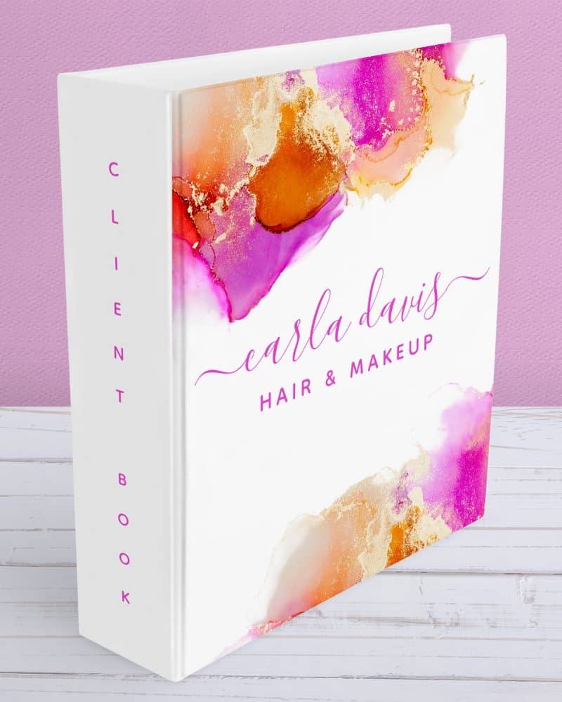White client book with pink and gold alcohol ink design and Carla Davis Hair & Makeup text.