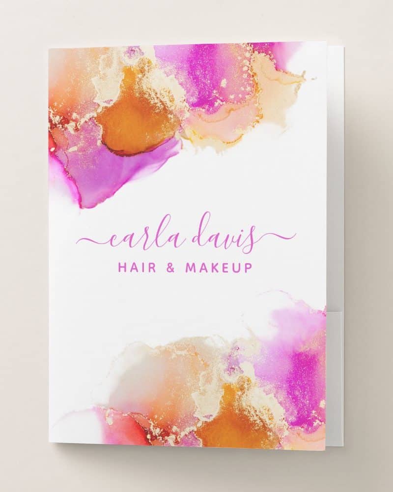 Hair and makeup artist Carla Davis's business card featuring an abstract design of pink, orange, and gold watercolor.