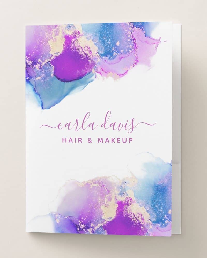 A pocket folder featuring an abstract design of purple, blue, and gold watercolor, with the name Carla Davis Hair & Makeup.