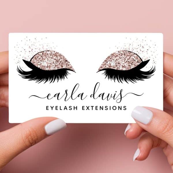 A Business Card For Carla Davis Eyelash Extensions Featuring A Pair Of Eyes With Rose Gold Glitter Eyeshadow And Long Lashes.