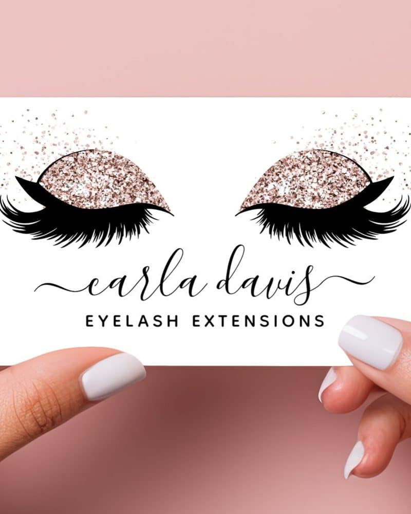 A business card for Carla Davis Eyelash Extensions featuring a pair of eyes with rose gold glitter eyeshadow and long lashes.