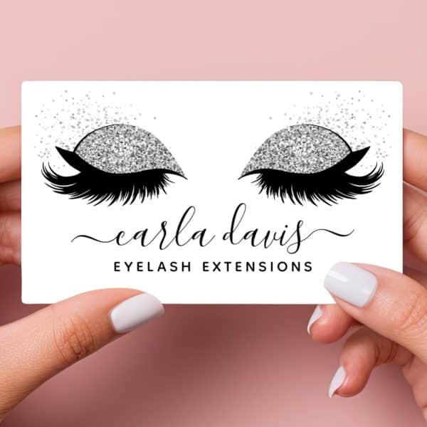 A Business Card Featuring A Pair Of Eyes With Long Lashes And Silver Glitter Eyeshadow. The Text Carla Davis Eyelash Extensions Is Below.