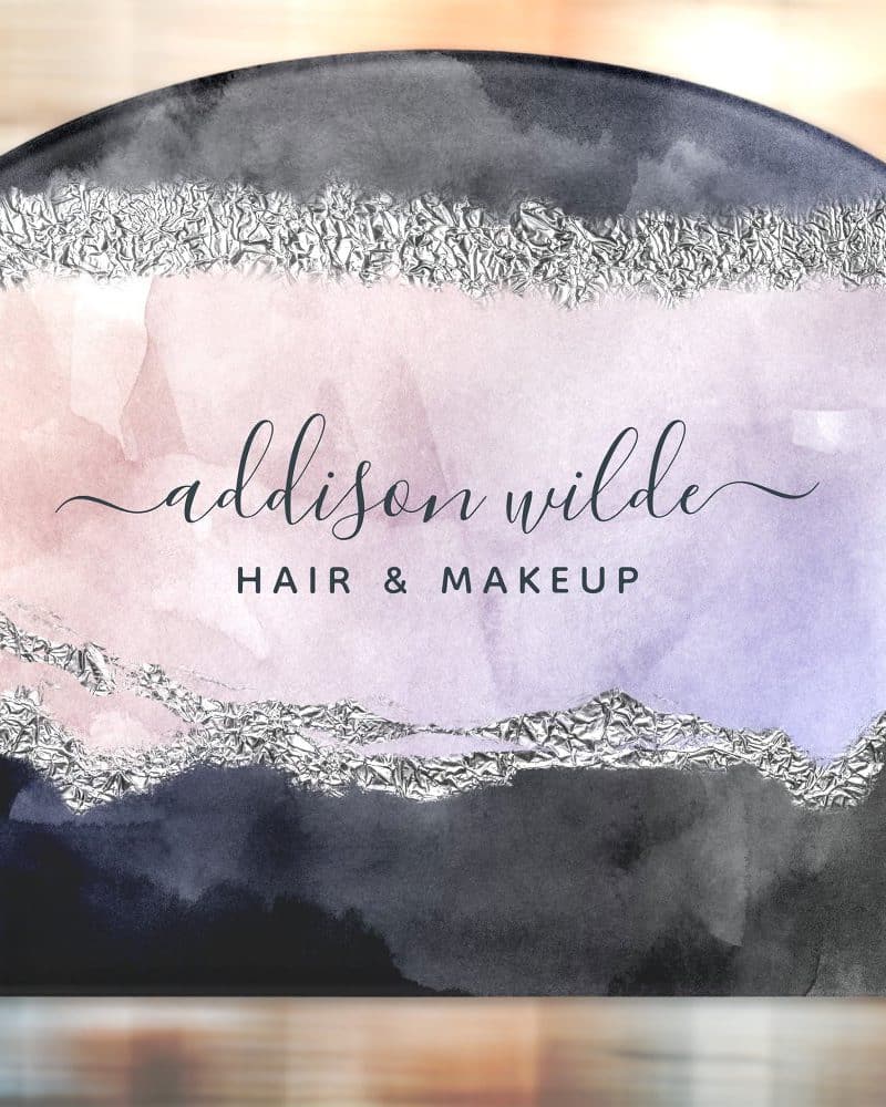 Arched business sign for Addison Wilde Hair & Makeup. The sign features a watercolor design in shades of purple, pink, and gray, accented with silver foil.