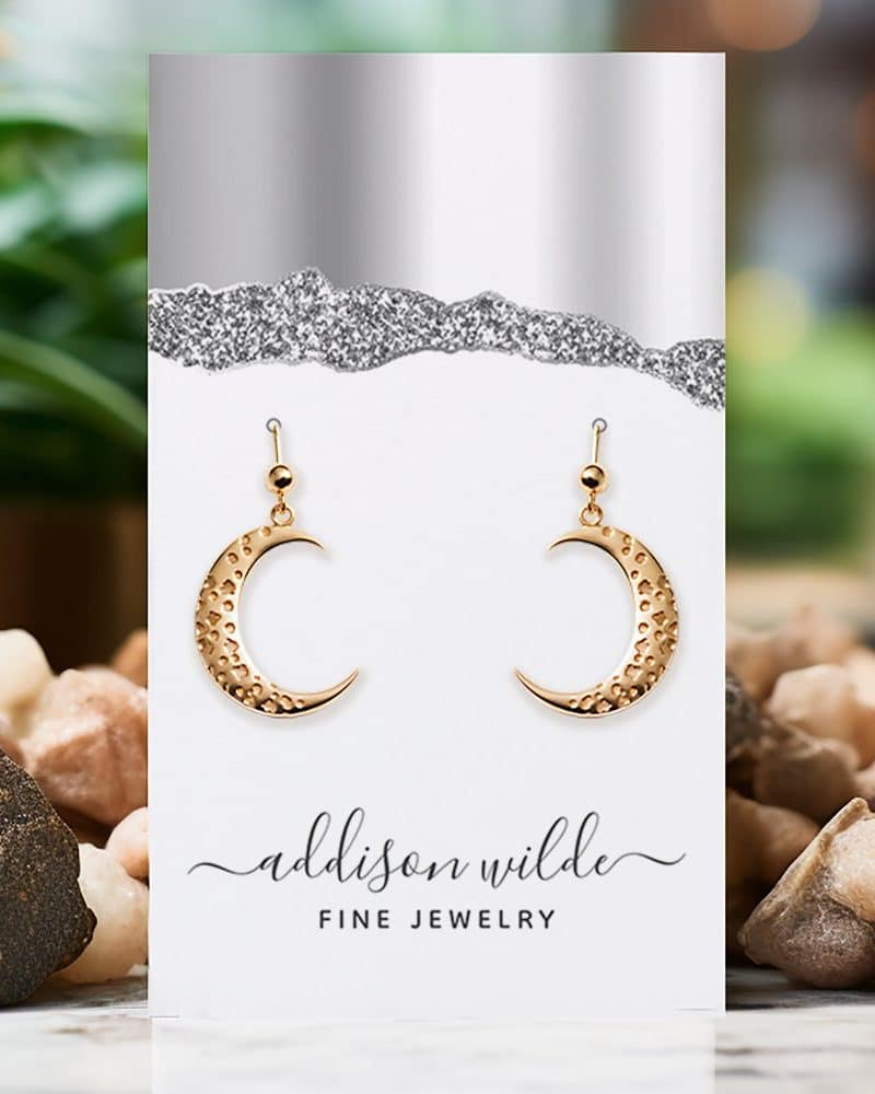 Gold crescent moon earrings displayed on a jewelry card.