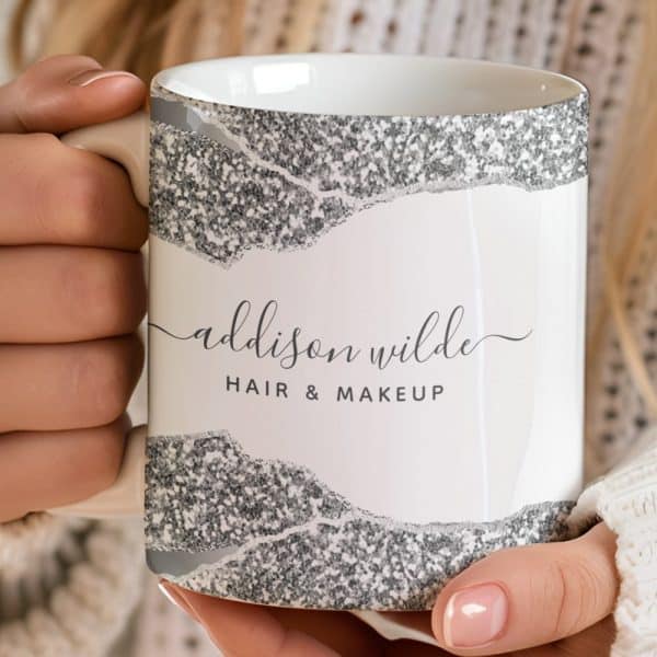 A White Coffee Mug With Silver Glitter Accents And The Name Addison Wilde, Hair &Amp; Makeup, Is Held In Two Hands.