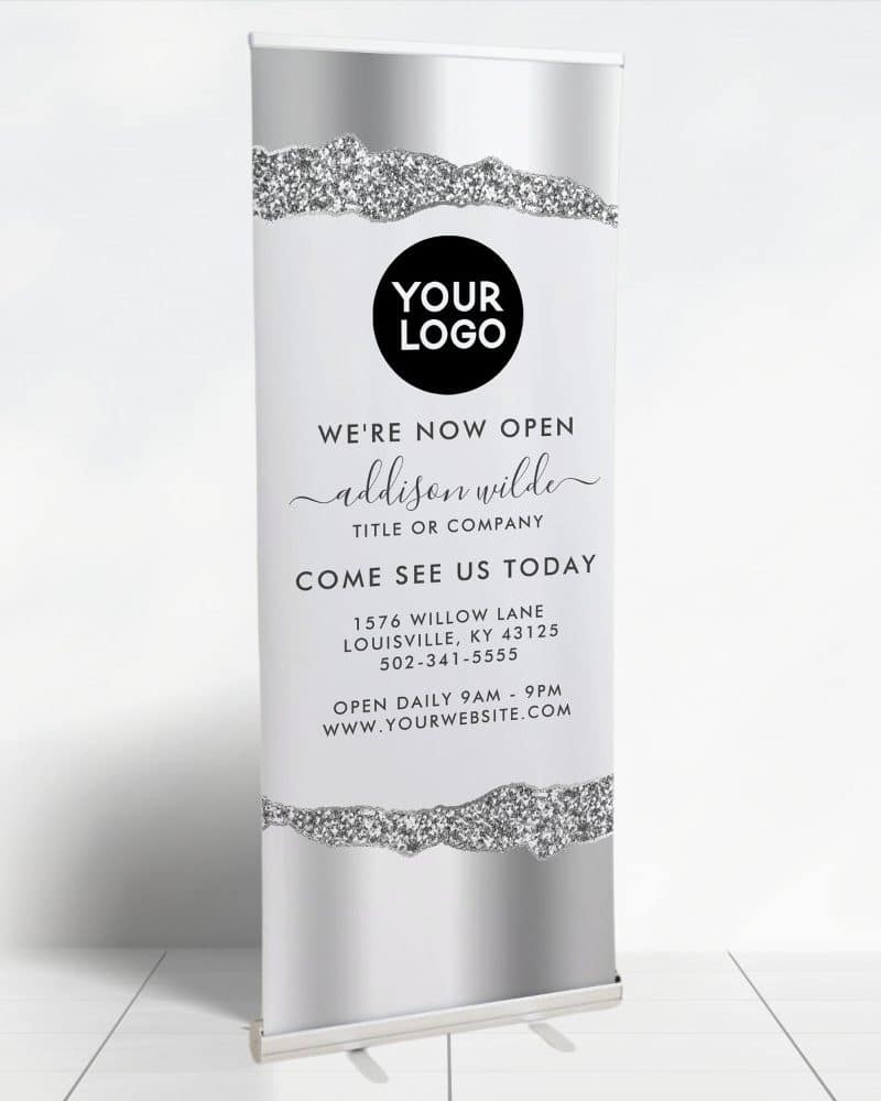 Silver and gray retractable banner announcing a new business opening, featuring a sparkly design element.
