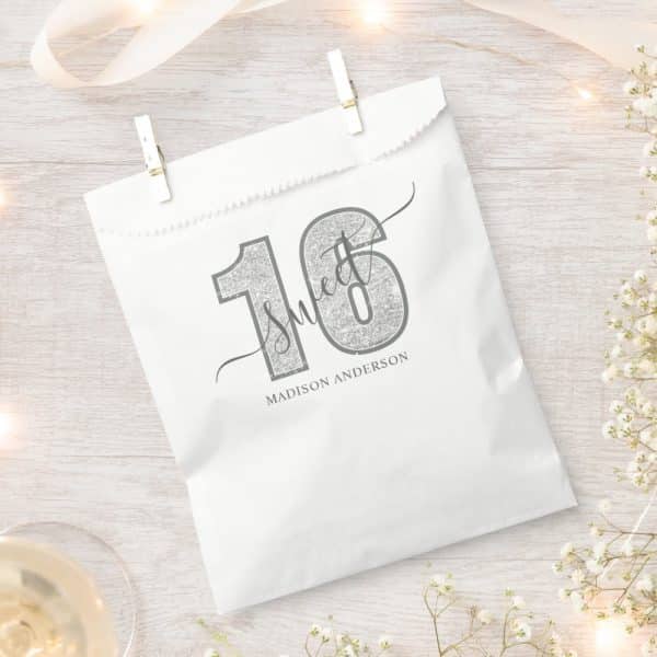 Silver Glitter-Textured Number Sixteen With The Word Sweet And Madison Anderson'S Name Printed On A White Gift Bag.
