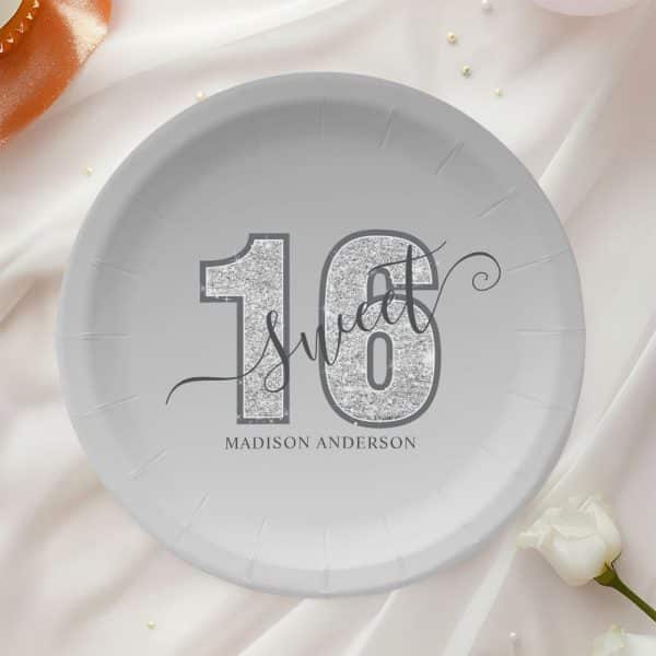 A Gray Paper Plate With Silver Glitter Sixteen And The Words Sweet Sixteen. Madison Anderson Is Printed Below.
