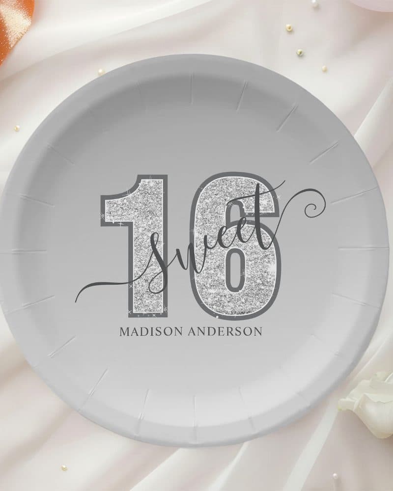 A gray paper plate with silver glitter sixteen and the words Sweet Sixteen. Madison Anderson is printed below.