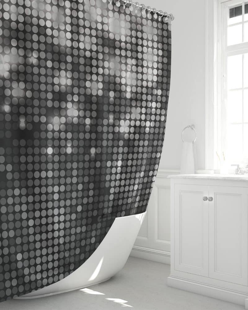 Black and white dotted shower curtain partially draped over a white bathtub.