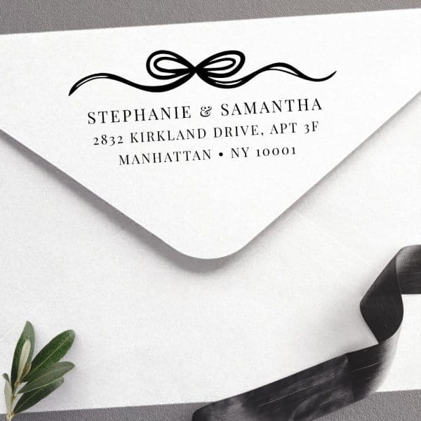 Return Address Stamp On A White Envelope, Featuring A Decorative Ribbon Design Above The Names Stephanie &Amp; Samantha And Their Manhattan Address.