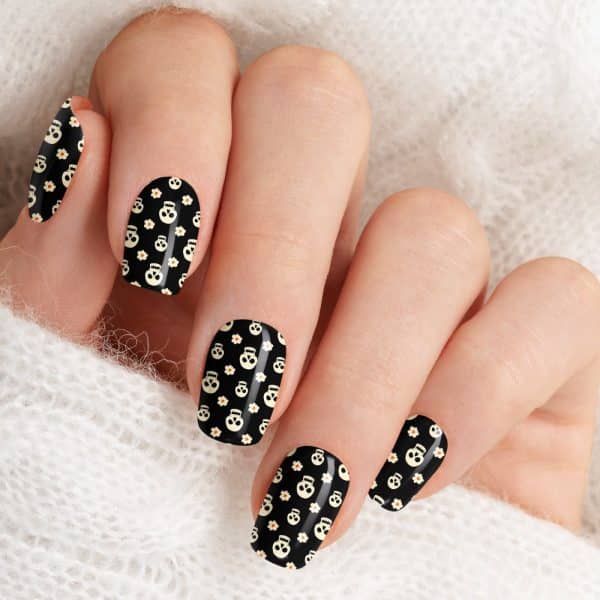 Close Up Of A Hand With Fingernails Decorated With A Black And Off-White Skull And Flower Pattern.